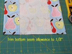 a piece of fabric with apples on it next to a pair of scissors and a ruler