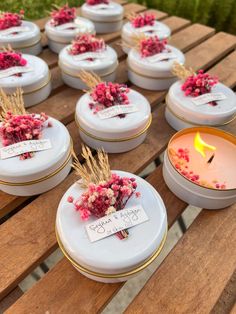 many small white dishes with flowers on them are sitting on a wooden table next to a candle