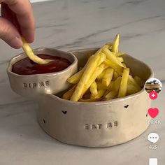a person dipping fries into a bowl with ketchup and mustard on the side