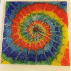 a multicolored tie - dyed piece of paper on a white surface with scissors next to it