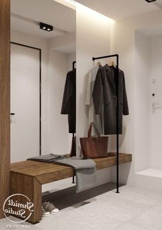 a white bathroom with a wooden bench and coat rack