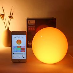 a smart phone sitting next to an illuminated ball on a table in front of a box