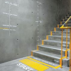 a set of stairs with yellow handrails in front of a concrete wall that reads start