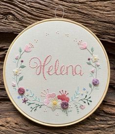 a white embroidered hoop with pink flowers and the word hello written in cursive writing