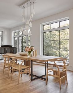 a dining room table and chairs in front of large windows