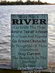 a sign that is sitting on the side of a wooden dock near water and trees