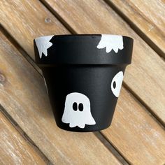 a black pot with white ghost faces painted on it