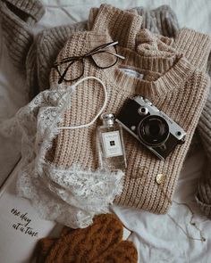 a sweater, hat, and camera on a bed