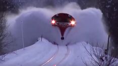 a train is coming down the tracks covered in snow as it speeds through the woods