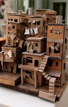 a cardboard model of a house with clothes hanging from it's windows and balconies on the roof