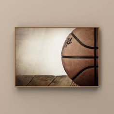 a basketball sitting on top of a wooden floor in front of a wall mounted frame