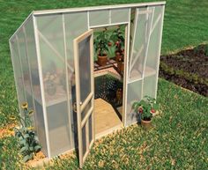 a small greenhouse in the grass with potted plants on it's sides and doors open