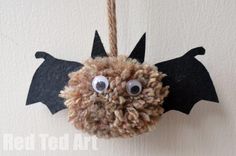 a paper bat hanging from a rope with eyes and hair on it's nose