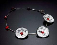 a white bracelet with red beads and flowers on the clasp is sitting on a black surface