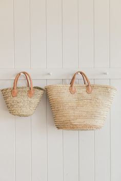 two straw bags hanging on the wall