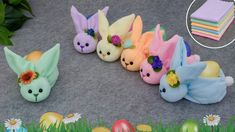 several small stuffed animals are lined up on the ground next to some eggs and flowers