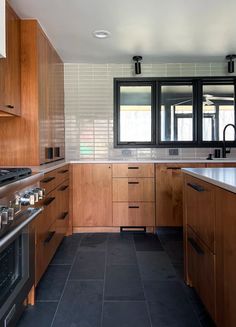a kitchen with wooden cabinets and black tile flooring