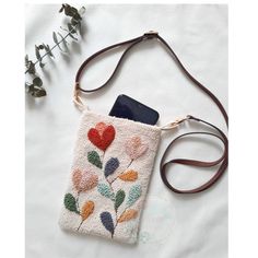 a cell phone case with flowers on it and a brown leather strap is laying on a white sheet