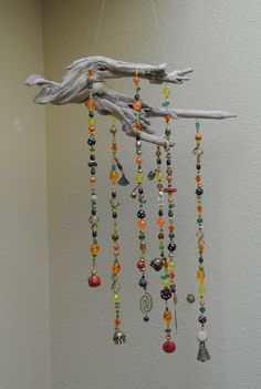 a wind chime hanging from a tree branch with beads and charms attached to it