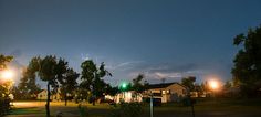lightning strikes in the sky over houses and trees at night time with green street lights