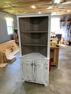 an old china cabinet in a garage with wood flooring