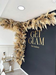 a sign that says get glam on the side of a wall with feathers hanging from it