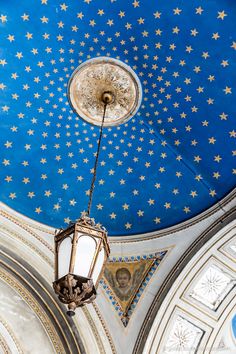 an ornate ceiling with blue and gold stars painted on the ceiling is lit by a light fixture