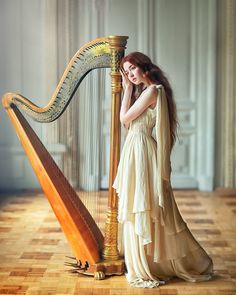 a woman in a long dress is holding a harp