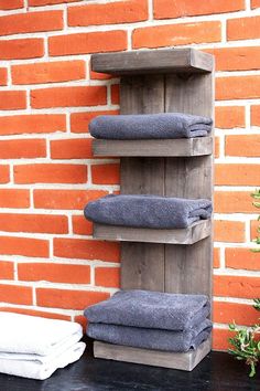 a wooden shelf with towels on it next to a brick wall