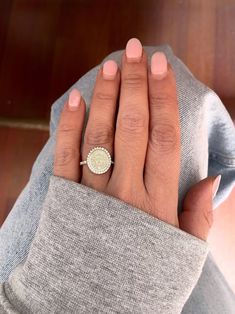 a woman's hand with a ring on top of her finger and a sweater