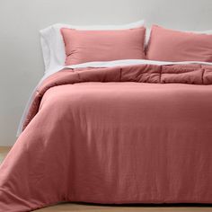 a bed with pink sheets and white pillows