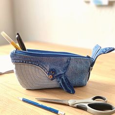 a pair of scissors and pencils are sitting in a denim pouch on a table
