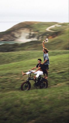 two people riding on the back of a dirt bike while one person holds up a frisbee