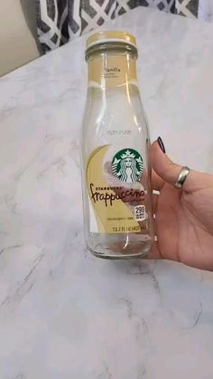 a hand holding a starbucks coffee bottle on top of a table
