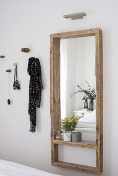 a wooden mirror hanging on the wall next to a plant and potted plant in front of it