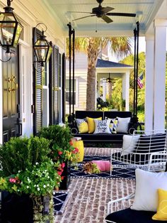 the porch is decorated with black and white furniture, yellow pillows, and potted plants