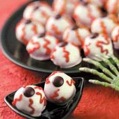 halloween treats are arranged in the shape of hands and balls on a black plate with pink border