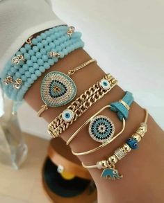 a woman's arm with several bracelets on it and an eye charm in the middle