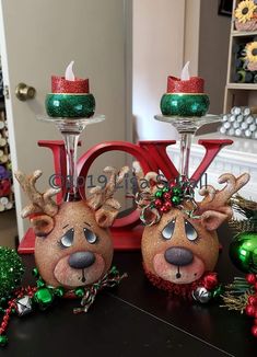 two wine glasses decorated with reindeer heads and red candlesticks, sitting on a table