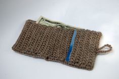 a brown crocheted pouch with a blue line on the side and one dollar bill sticking out of it