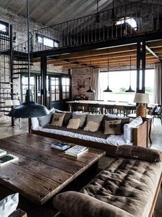 a living room filled with lots of furniture next to a brick wall and ceiling covered in windows