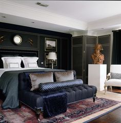 a large bed sitting next to a black couch in a bedroom on top of a wooden floor
