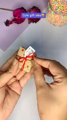 two hands holding small gift boxes with candy in them