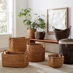 several woven baskets sitting on the floor in front of a window with a potted plant