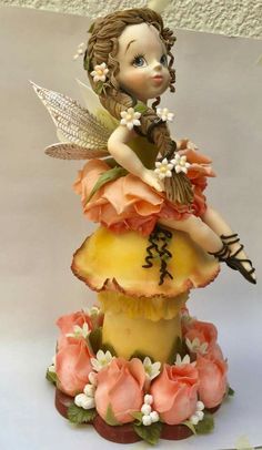 a figurine sitting on top of a cake covered in frosting and flowers