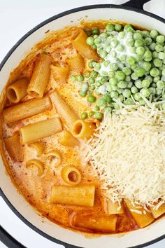 pasta, peas and cheese are in a pan on the stove top with other ingredients