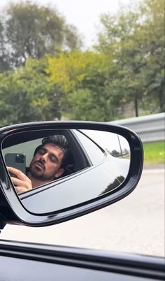 a man taking a selfie in the side mirror of a car