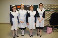 four women dressed in maid outfits standing next to each other