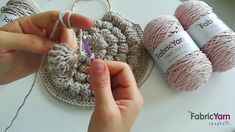 someone is crocheting together with yarn on a white table and two balls of yarn are next to each other
