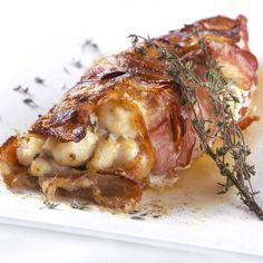 a piece of meat sitting on top of a white plate covered in sauce and herbs
